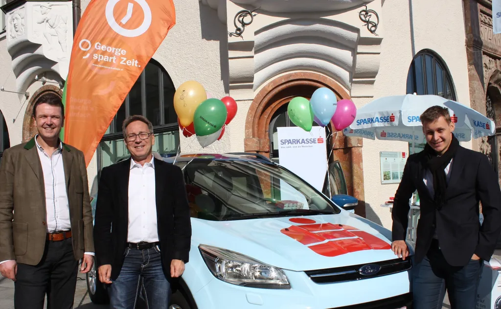 drei Männer stehen neben Sparkasse foliertem Auto 