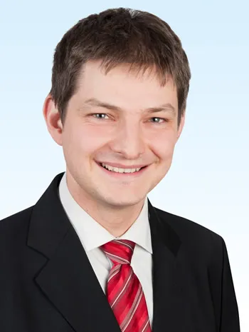 Herr mit roter Krawatte lächelt in die Kamera