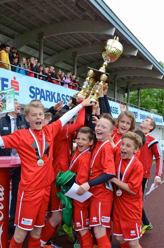 lachende Kinder mit Pokal in der Hand