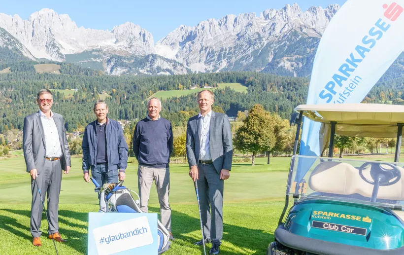 4 Heren stehen im freien auf einem Golfplatz und lächeln in die Kamera