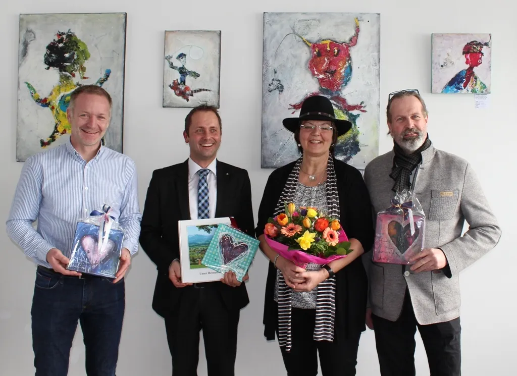 vier Personen mit Blumen und Bild in der Hand