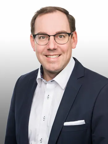 Herr mit Brille lächelt in die Kamera