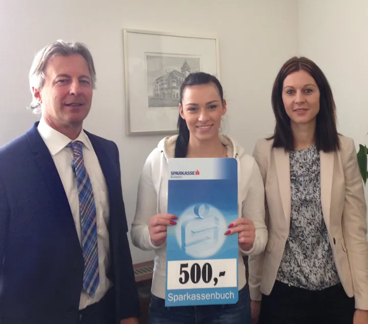 eine Frau in der Mitte hält ein Sparbuch in der Hand und eine Frau und ein Mann stehen nebenan 