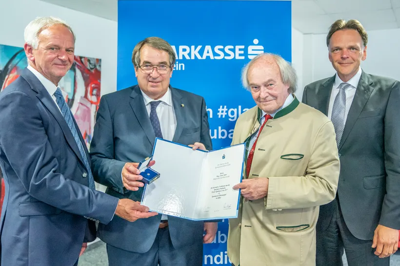 vier Herren halten ein Dokument in die Kamera