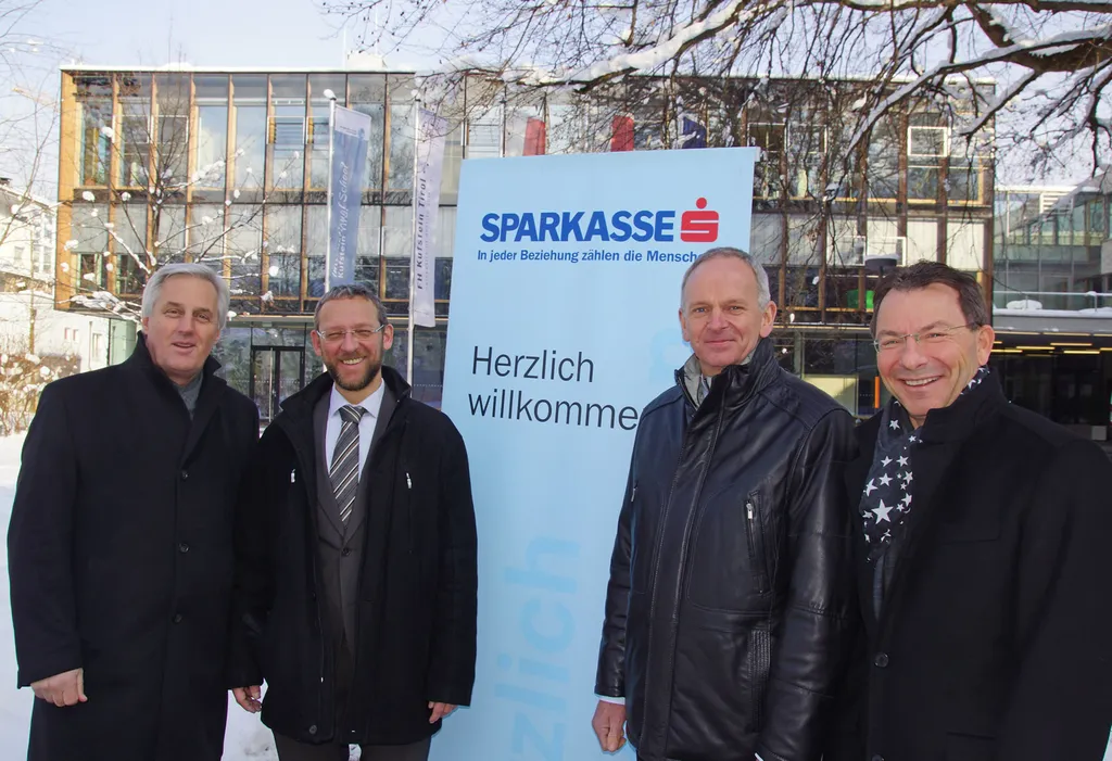 vier Männer neben Herzlich Willkommen Sparkasse Aufsteller 