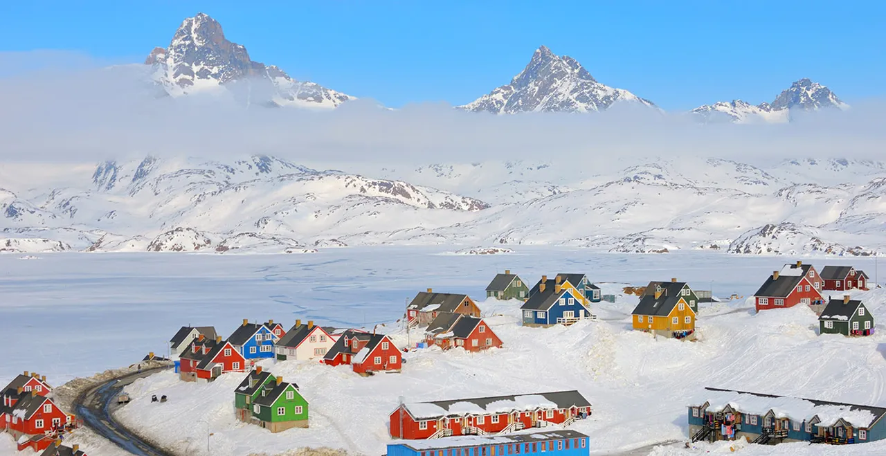 Ein Ort in Grönland - typische bunte Häuser, umgeben von Schnee- und Berglandschaft