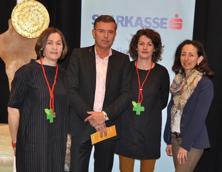 drei Frauen und ein Mann lachen stehend in die Kamera