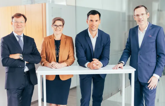 Fünf Menschen stehen an einem Stehtisch