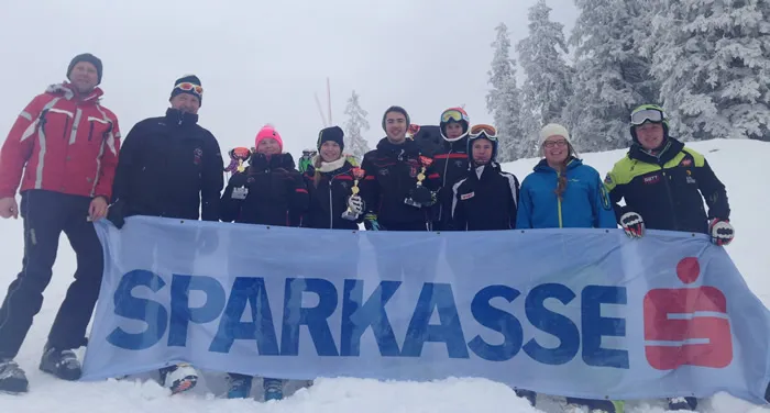 Eine Gruppe von Menschen hält das Sparkasse Banner im Schnee in Ski-Kleiding