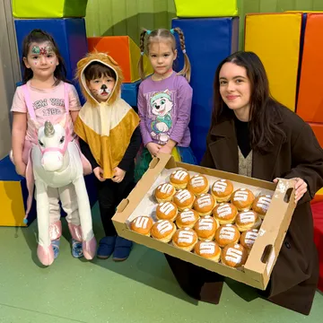 Kundenberaterin mit drei Kinderkartenkinder und Faschingskrapfen