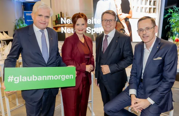 Drei Männer und eine Frau stehen zusammen und lächeln in die Kamera.