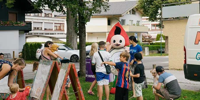 Sparefroh umringt von Kindern im Freien