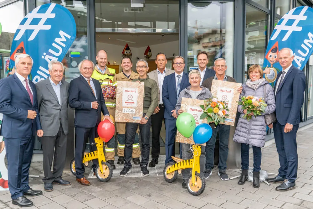 Personen vor Sparkasse Eingang mit Spendenübergabe