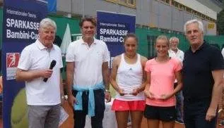 zwei Mädchen mit Pokal in der Hand und drei Männer nebenan lachen in die Kamera