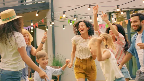 Familie und Freunde lachen und tanzen zusammen im Garten