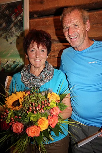 eine Frau mit einem Blumenstrauß in der Hand und ein Mann lachen in die Kamera