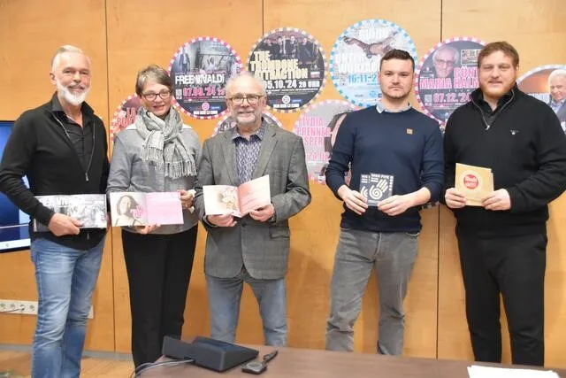 5 Personen mit Programmheften in den Händen blicken in die Kamera