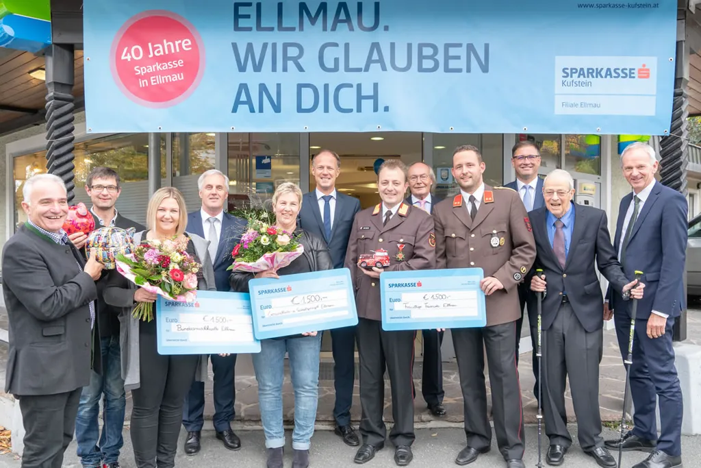 vor Sparkasse stehen drei Personen mit Spendentafel in der Hand und acht Personen nebenan