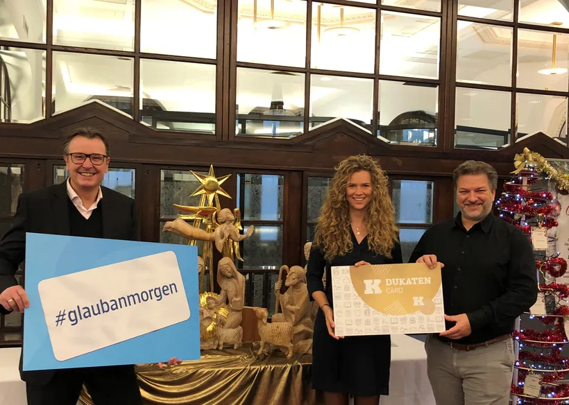 3 Personen halten Schilder in die Kamera und lächeln