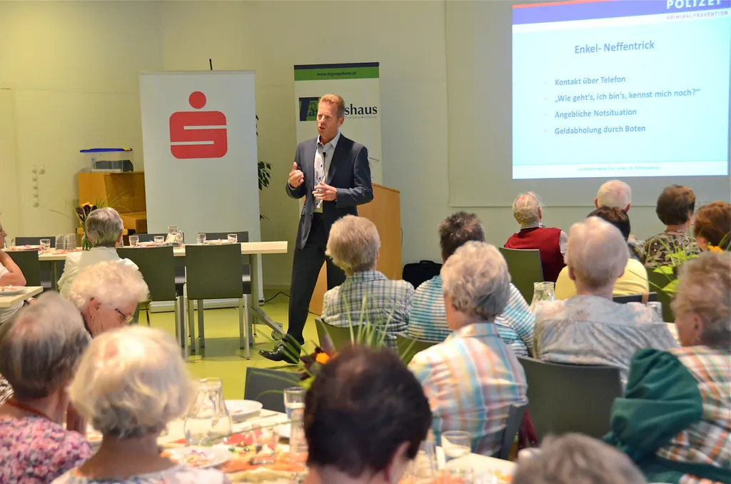 sprechender Mann vor sitzenden Personen