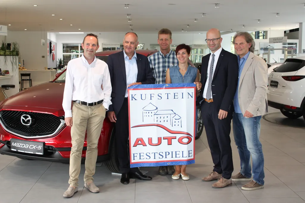 sechs Personen vor rotem Auto halten Plakat