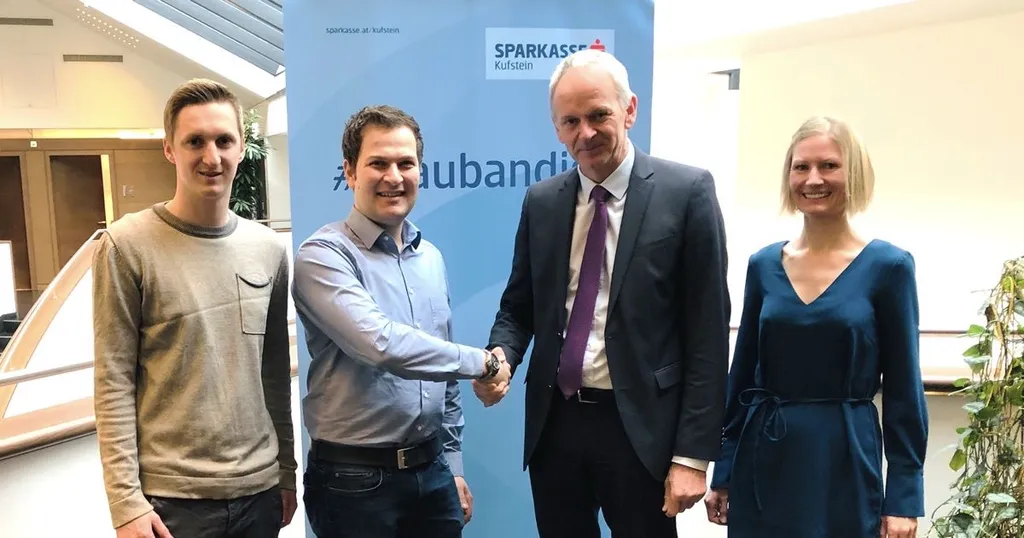 4 Personen vor dem Sparkasse Kufstein Aufsteller lachen in die Kamera, die beiden Herren in der Mitte schütteln sich die Hand