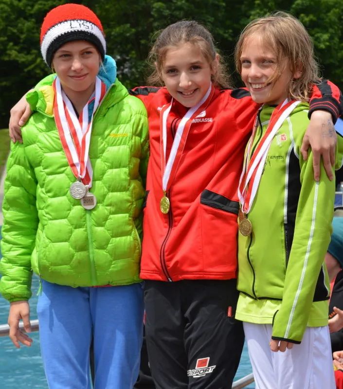 drei Medaille um den Hals schauen in die Kamera