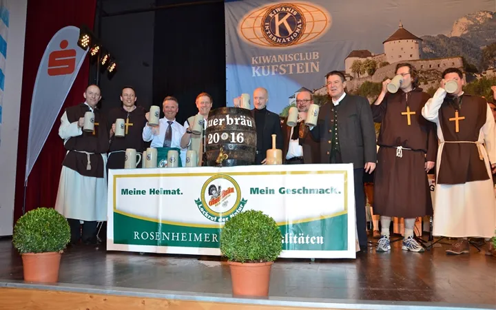 viele Männer stehen auf der Bühne mit einem Bierfass und Bierkrug in der Hand 