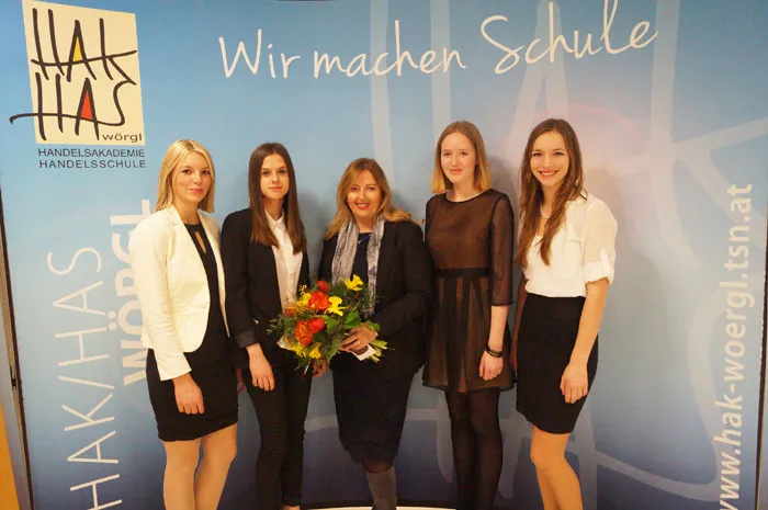 Eine Gruppe junger Frauen lacht in die Kamera vor dem Banner der HAK Wörgl