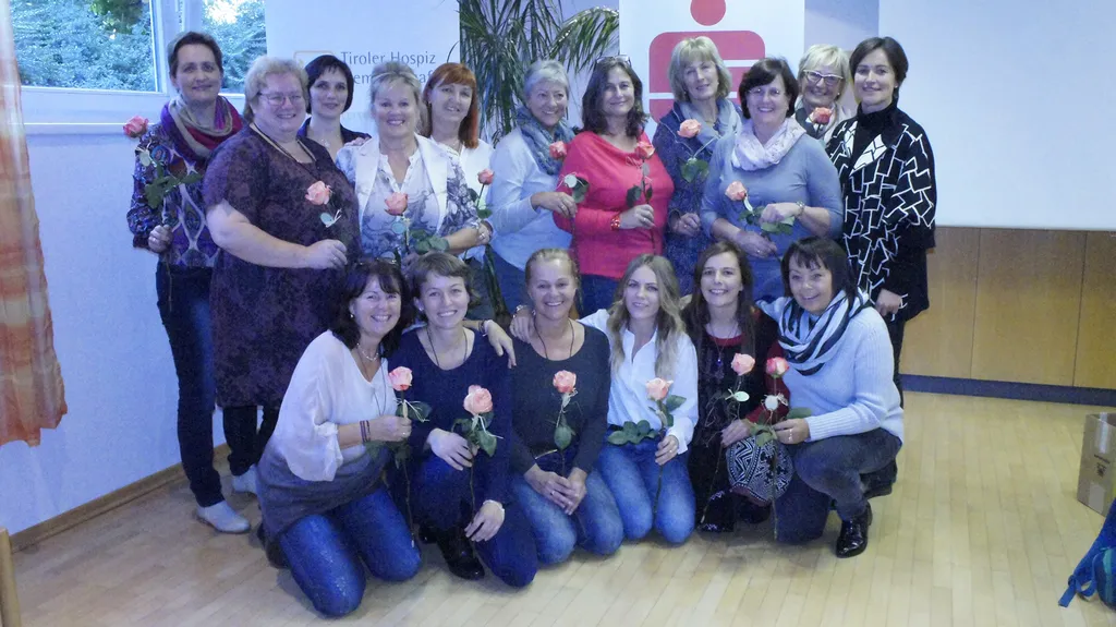 Gruppenbild von lachenden Frauen mit einer Rose in der Hand