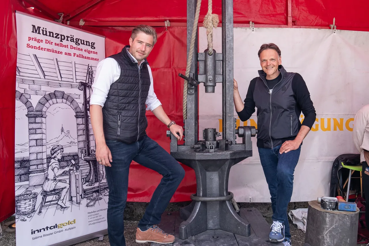 zwei Herren stehen bei einer Maschine für Münzprägung